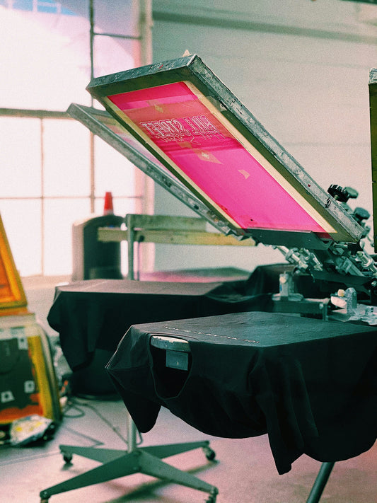 Screen printing press with pink screen. Cover photo for how screen printing works article.